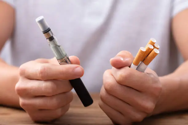 Image holding vape and cigarettes