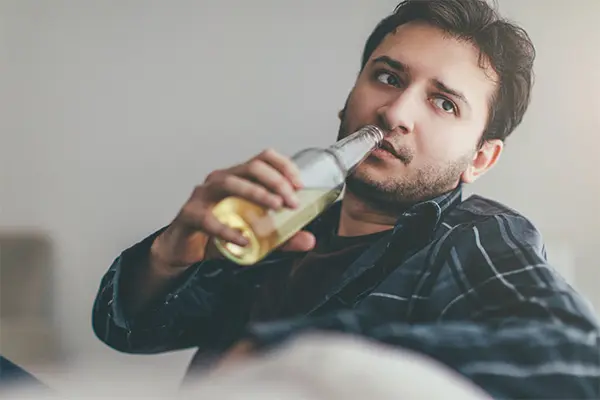 Person struggling with alcohol drinking a beer